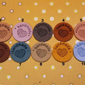 May include: Ten round leather tags with the word "handmade" and a heart design in various colours, including brown, pink, blue, and tan.