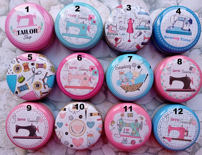 Op de afbeelding: Een verzameling van twaalf ronde, decoratieve blikken met naaigerelateerde ontwerpen. De blikken tonen afbeeldingen van naaimachines, garen, scharen en de tekst "Tailor Shop", "I love Sewing" en "Sewing Time". De blikken zijn in verschillende kleuren, waaronder roze, blauw en wit.