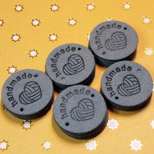 May include: Six black round labels with the word "handmade" and a stylised heart with yarn inside. The labels are stacked on top of each other.