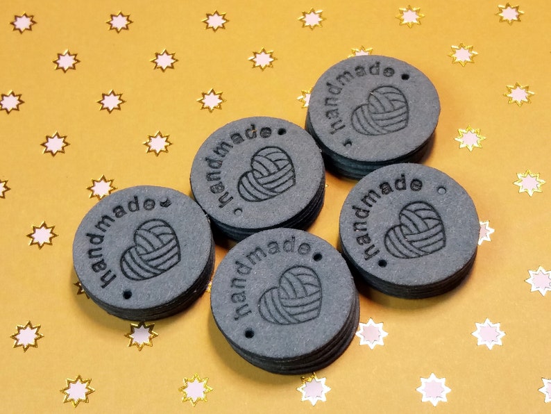 May include: Six black round labels with the word "handmade" and a stylised heart with yarn inside. The labels are stacked on top of each other.