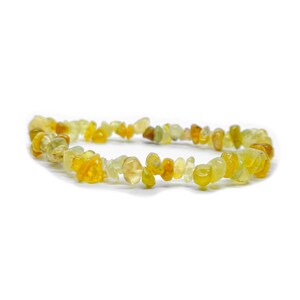 Peut inclure: Un bracelet composé de petites pierres précieuses jaunes et ambrées de forme irrégulière. Les pierres sont enfilées ensemble, créant un bracelet souple. Le bracelet est posé sur un fond blanc.