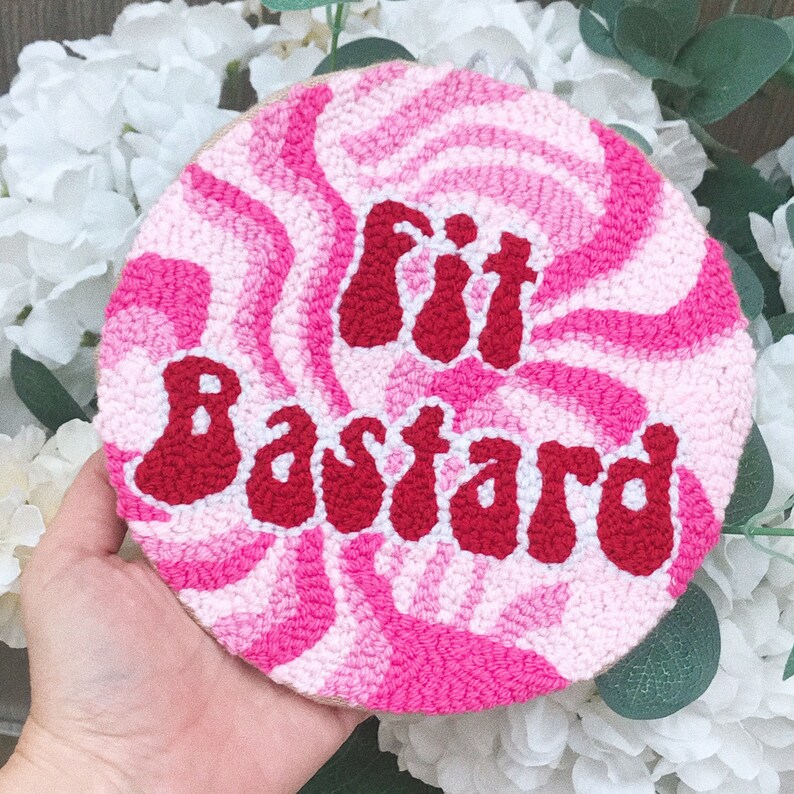 Puede incluir: Un patr&oacute;n de espiral rosa y blanco con la frase "Fit Bastard" en letras rojas. La frase est&aacute; en un estilo de fuente retro.