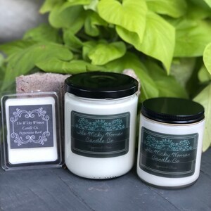 Könnte beinhalten: Drei Glaskerzenbehälter mit schwarzen Deckeln. Die Behälter sind mit weißem Wachs gefüllt und haben Etiketten mit dem Text "The Wicky Woman Candle Co. Peppermint Bark".