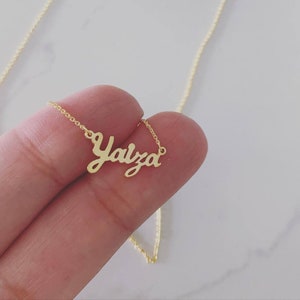 May include: A gold necklace with the name "Yalza" written in cursive script.