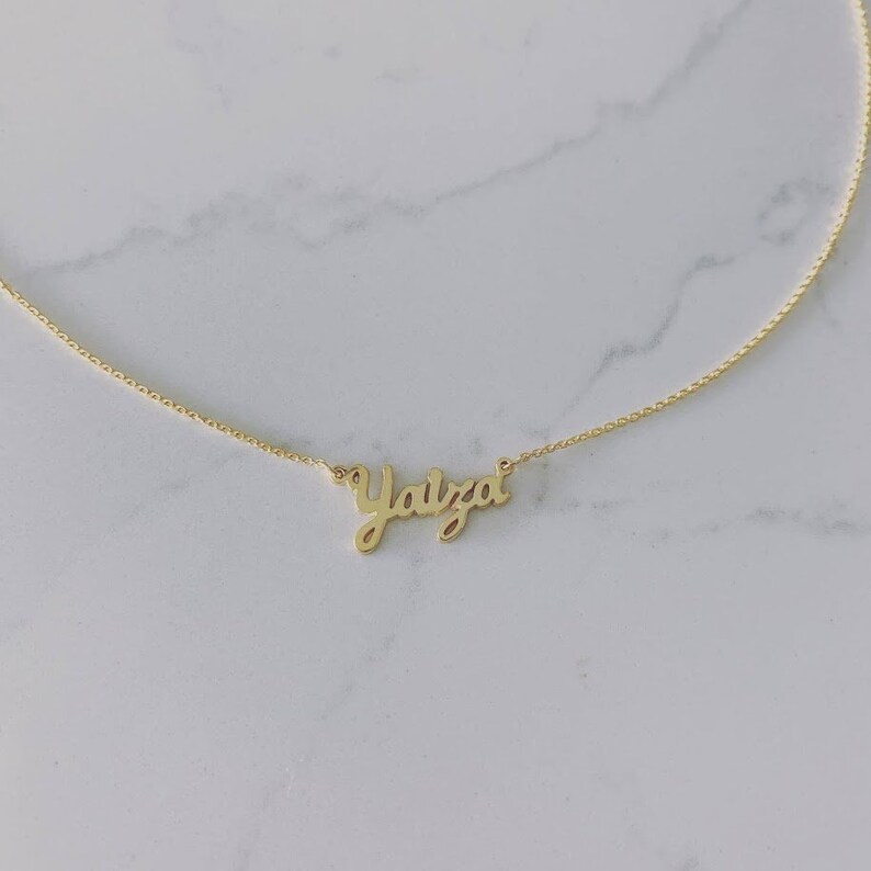 May include: A gold chain necklace with the name "Yaizal" written in cursive on a pendant.
