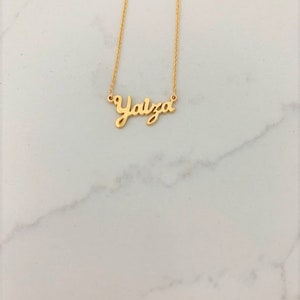 May include: A gold necklace with the name "Yalza" written in cursive.