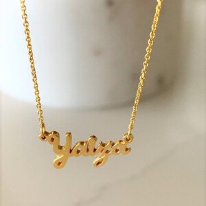 May include: Gold necklace with the name "Yaiza" written in a cursive script.