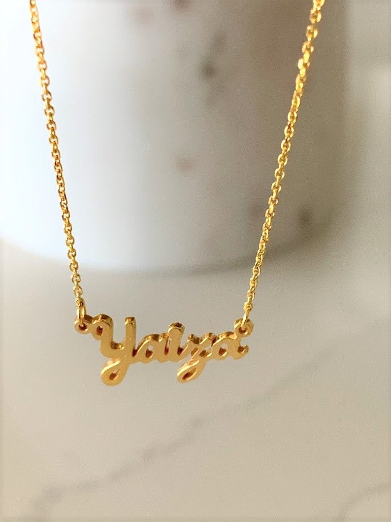 May include: Gold necklace with the name "Yaiza" written in a cursive script.