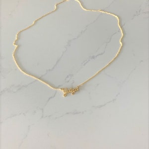 May include: A gold chain necklace with a delicate pendant that reads "Yaitza".