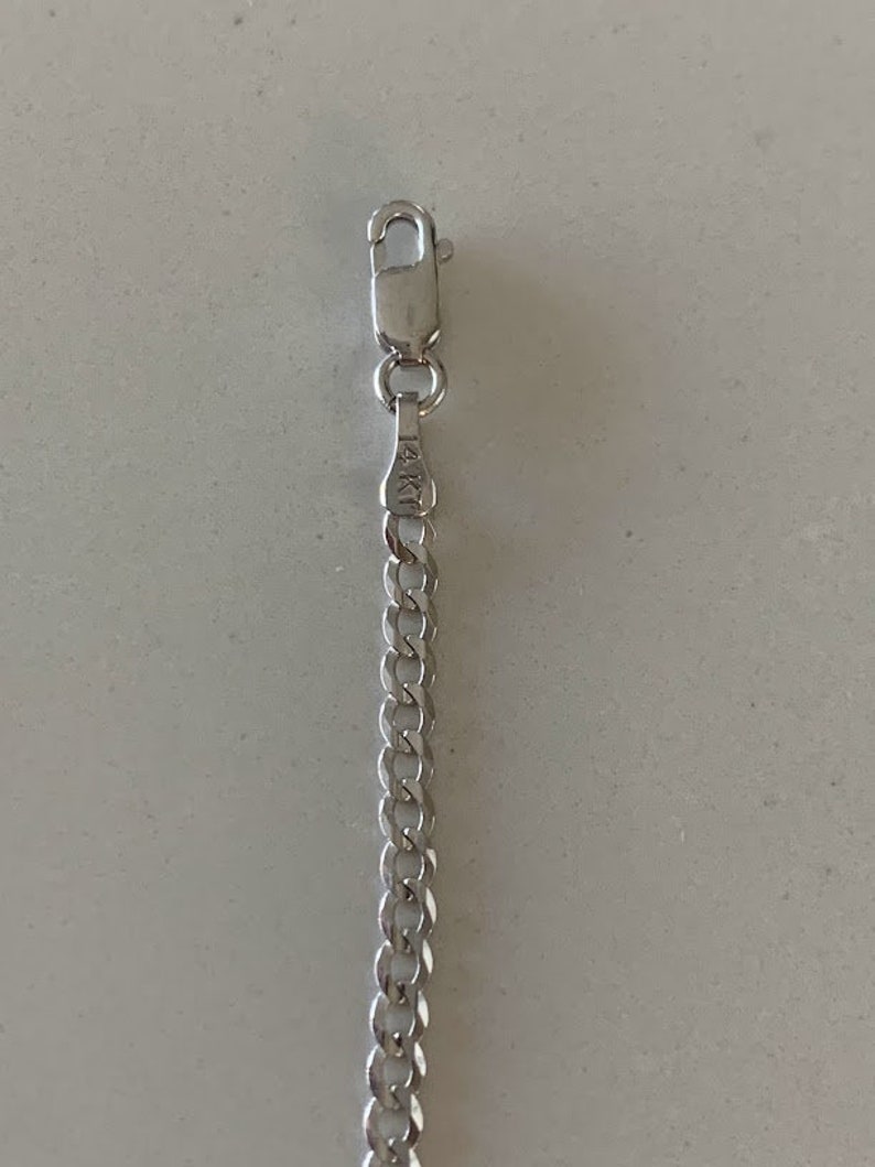 Puede incluir: Un collar de cadena de plata con un cierre de langosta. La cadena est&aacute; hecha de peque&ntilde;os &oacute;valos unidos. El cierre tiene la inscripci&oacute;n "14KT" en &eacute;l.