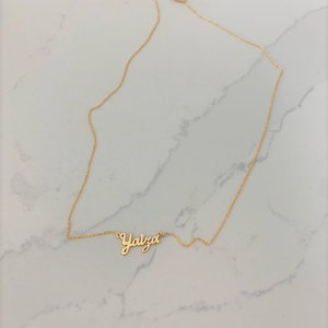 May include: A gold chain necklace with a cursive name pendant that reads "Yalza".