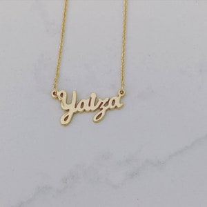 May include: A gold necklace with the name "Yaiza" written in a cursive font.