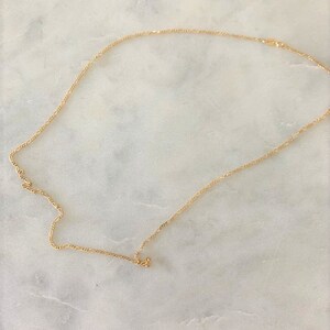 May include: A gold chain necklace with a delicate, twisted design.