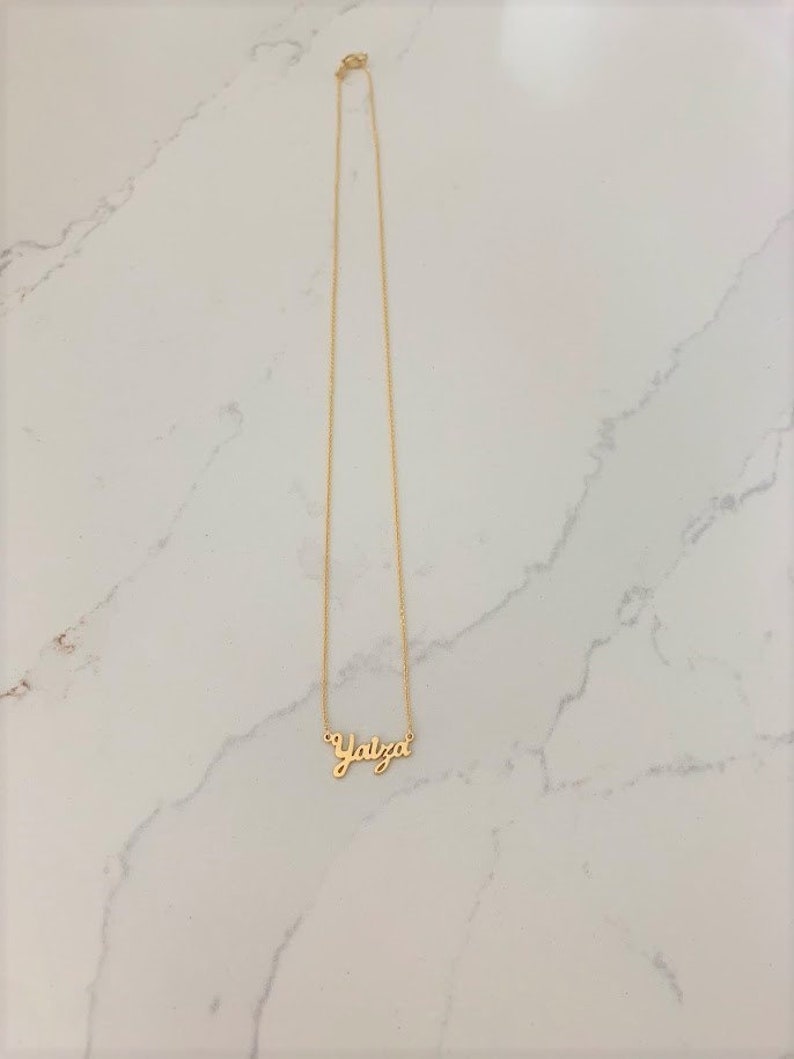 May include: A gold chain necklace with the name "Yaiza" spelled out in cursive.