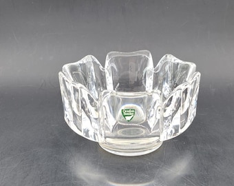 Könnte beinhalten: Eine klare Glasschüssel mit geometrischem Design. Die Schüssel hat einen kleinen, runden Boden und eine breite, offene Oberseite. Die Schüssel ist aus dickem, schwerem Glas gefertigt und hat eine leichte grüne Tönung.
