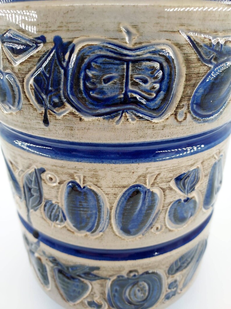 Peut inclure: Un pot en c&eacute;ramique blanche avec un motif floral bleu et blanc. Le pot a une large ouverture et un fond arrondi. Le motif floral pr&eacute;sente des feuilles et des fruits stylis&eacute;s.