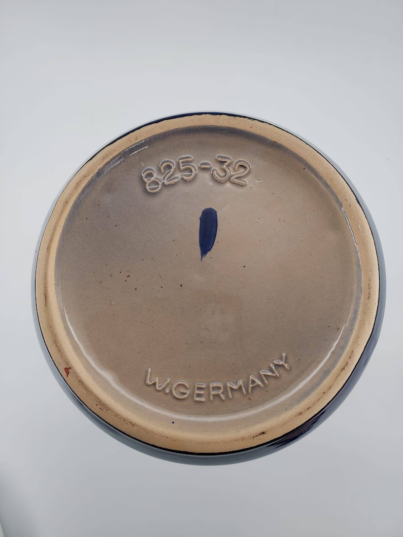 Peut inclure: Le dessous d'un vase en c&eacute;ramique bleu avec le num&eacute;ro "825-32" et le texte "W. Germany" imprim&eacute; au fond.