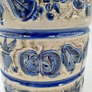 Peut inclure: Un vase en c&eacute;ramique blanche avec des motifs floraux bleus. Le vase a une surface textur&eacute;e et est d&eacute;cor&eacute; de fleurs, de feuilles et de baies bleues.
