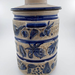 Peut inclure: Un pot en c&eacute;ramique avec un motif bleu et blanc repr&eacute;sentant une vari&eacute;t&eacute; de fruits. Le pot a un couvercle et une poign&eacute;e.