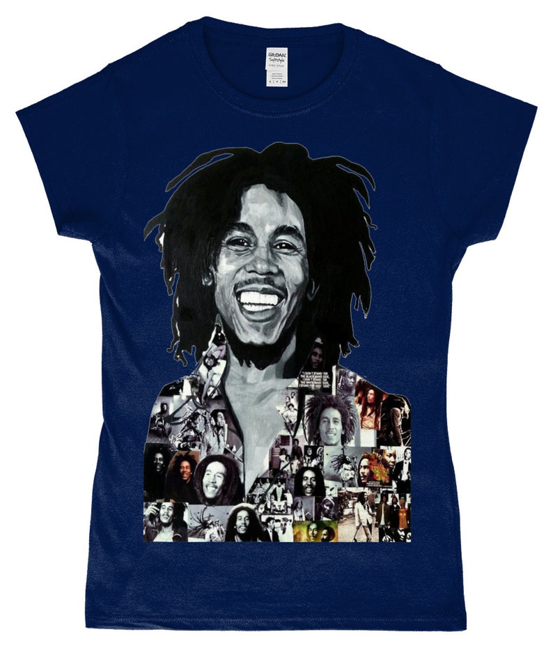 May include: A navy blue t-shirt featuring a black and white photo collage of Bob Marley. The collage includes various images of Marley, including a close-up of his face with a wide smile.