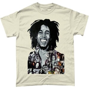 Op de afbeelding: Een beige T-shirt met een zwart-witte afbeelding van Bob Marley. De afbeelding is een collage van verschillende foto's van Marley, waaronder close-ups van zijn gezicht en foto's van hem tijdens optredens.