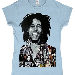 May include: A light blue t-shirt featuring a black and white portrait of Bob Marley. The portrait is a collage of smaller images of Bob Marley.