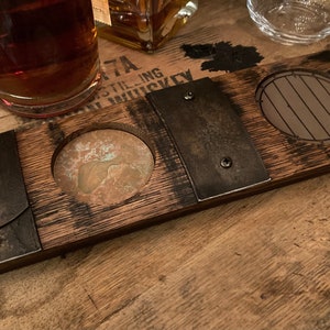 May include: A wooden whiskey barrel stave serving tray with three recessed areas. The tray has metal accents and is designed to hold a cigar, a glass, and a drink. The wood has a dark finish and visible grain.