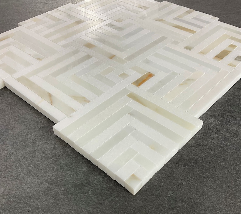 May include: White marble tile mosaic with a geometric pattern. The tiles are arranged in a herringbone pattern, creating a modern and stylish look.