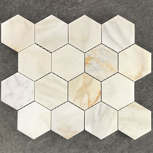 May include: A sheet of white and beige marble hexagon tiles. The tiles are arranged in a honeycomb pattern.