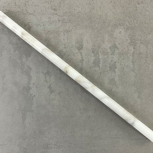 May include: A white marble rod with brown veining. The rod is smooth and polished.