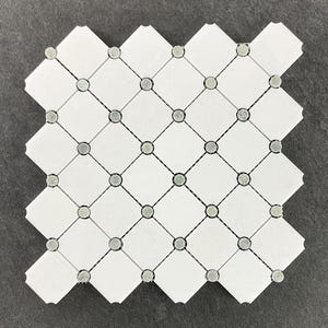 May include: White mosaic tile sheet with a diamond pattern. The design features white diamond-shaped tiles connected by gray lines and small, round, gray and green accents at the intersections. The tile sheet has a unique, scalloped edge.