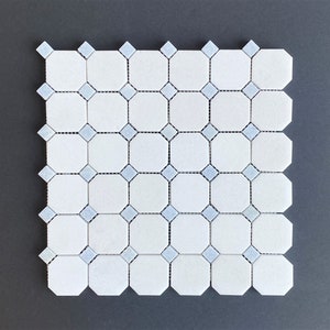 May include: White and light blue mosaic tile sheet. The tile sheet features a repeating pattern of octagonal white tiles with light blue diamond-shaped accents. The tiles are arranged in a grid pattern, creating a visually appealing design. Ideal for bathroom or kitchen projects.