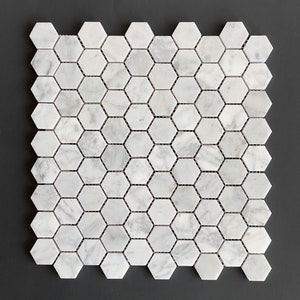 May include: A sheet of white marble hexagon tiles with a subtle gray veining. The tiles are arranged in a honeycomb pattern.