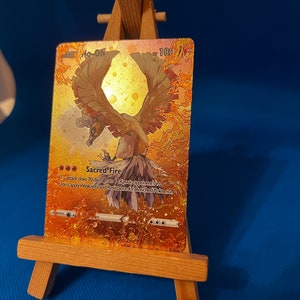 Pu&ograve; includere: Una carta Pok&eacute;mon dorata con effetto foil che presenta Ho-Oh, un Pok&eacute;mon uccello leggendario con colori arancio, giallo e rosso. Il testo della carta recita "Fuoco Sacro" e "Questo attacco infligge 70 danni a 1 dei Pok&eacute;mon del tuo avversario. Non applicare Debolezza e Resistenza per i Pok&eacute;mon Base."