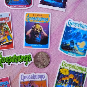 K&ouml;nnte beinhalten: Eine Sammlung von Goosebumps-Aufklebern und einer M&uuml;nze. Die Aufkleber zeigen Buchcover mit gruseligen Illustrationen und Titeln wie "The Haunted Mask" und "Attack of the Jack-O-Lanterns". Die M&uuml;nze ist von 1995.