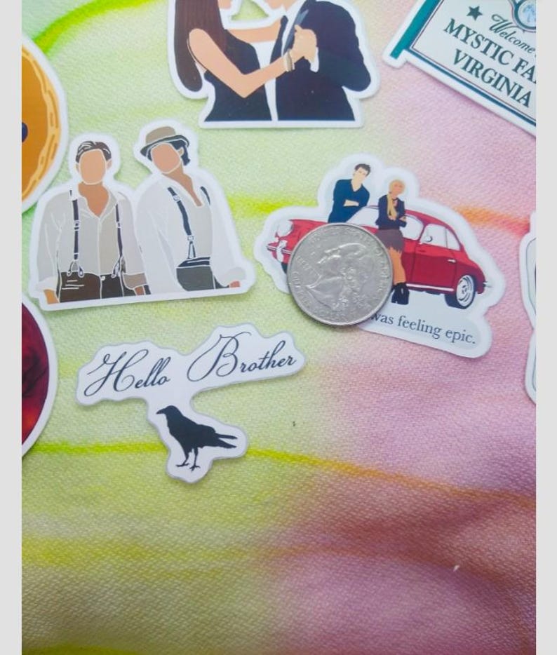 May include: A collection of stickers featuring illustrations of people, a red car, and the text "Hello Brother." The stickers are on a colorful, patterned background. A quarter is included for scale.