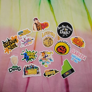 May include: A collection of colorful stickers featuring various cartoon characters and logos from popular 90s television shows. The stickers include text such as "Renan & Kel", "Doug", "Double Dare", "All That", "Clarissa Explains It All", and "Are You Afraid of the Dark?"