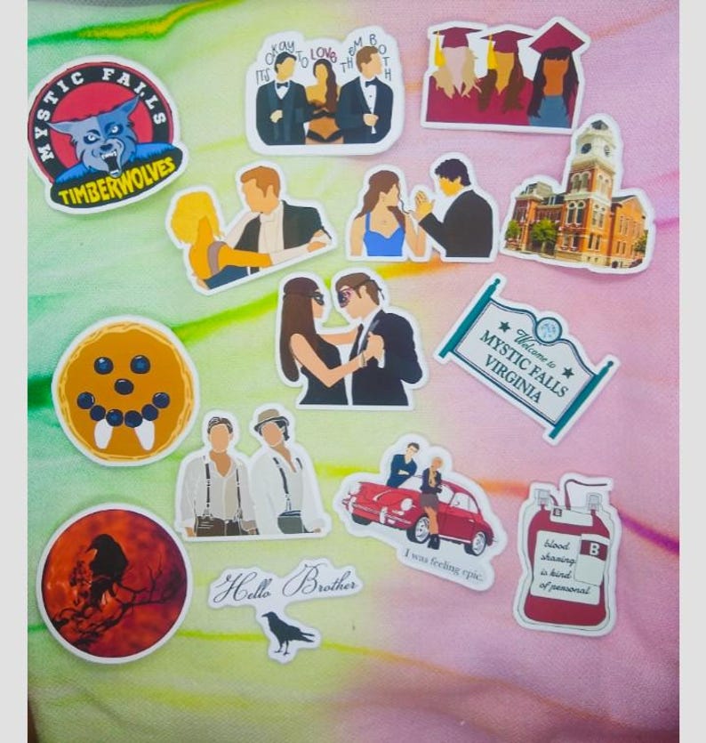 May include: A collection of colorful stickers featuring various designs. Included are stickers with the text "Mystic Falls Virginia", "Hello Brother", and "Mystic Falls Timber Wolves". Other stickers depict couples, a building, and a blood bag.