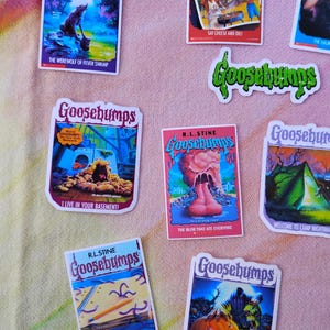 K&ouml;nnte beinhalten: Eine Sammlung von Goosebumps-Stickern mit verschiedenen Buchcovern. Titel sind "Der Werwolf vom Fiebersumpf", "Sag K&auml;se und stirb!", "Ich wohne in deinem Keller!", "Der Schleim, der alles fra&szlig;", "Willkommen im Camp Nightmare", "Esst W&uuml;rmer!" und "Kopfloses Halloween."
