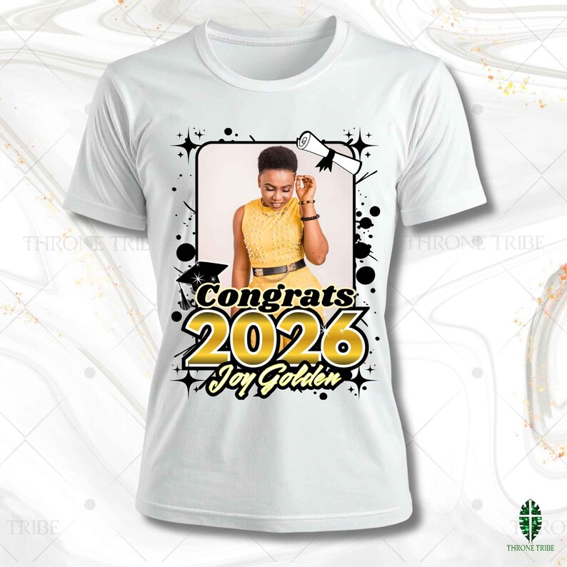 May include: White t-shirt featuring a graduation-themed design. The design includes a photo of a person in a yellow dress, the words "Congrats 2026" in gold, and the name "Joy Golden". The design is framed with black accents.
