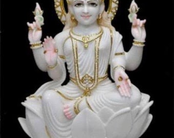 May include: White marble statue of the Hindu goddess Lakshmi, seated on a lotus flower with an elephant at her feet. She is adorned with gold jewelry and has a serene expression.