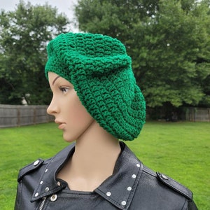 Peut inclure: Un béret en crochet vert. Le béret est porté par un mannequin avec une veste en cuir noir.