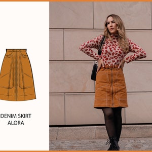 May include: A brown denim skirt with a front zipper and decorative stitching. The skirt is a-line and falls to the knee. The skirt is called "ALORA" in white text.