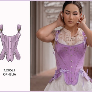 May include: A lavender corset with a lace-up front and a decorative bow at the bottom. The corset is called "Ophelia" and is shown on a model.