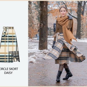 Peut inclure: Une femme portant une jupe circulaire en tissu écossais brun et noir avec une écharpe brune et des bottes noires. La jupe s'appelle "Circle Skort Daisy".