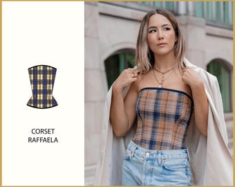 May include: A plaid corset with a black trim. The corset is strapless and has a fitted silhouette. The model is wearing the corset with a white blazer and blue jeans.