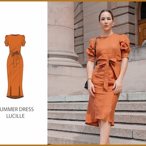 May include: A woman wearing a rust-colored summer dress with a tie belt and puff sleeves. The dress has a slit on the side. The dress is called "Lucille".