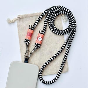 Chique telefoonketting van touw in zwart-wit. Zalmkleurig. Zilveren smileyhanger.