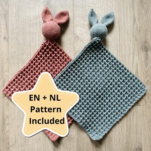 Puede incluir: Dos mantas de seguridad para bebés tejidas a ganchillo, una rosa empolvado y otra azul verdoso, con adornos de cabeza de conejito. Las mantas tienen un patrón de punto de gofre. Un gráfico en forma de estrella con el texto "EN + NL Pattern Included" está en la imagen.