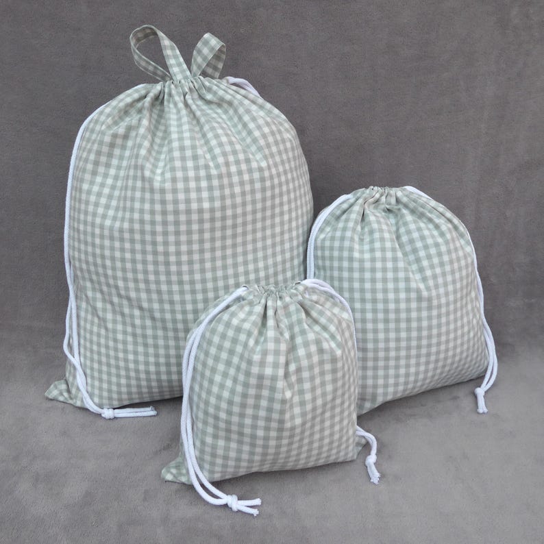 Handmade laundry bags and drawstring bags in light sage green gingham cotton rich canvas fabric with white cotton braided cords.
3 sizes available 
Small with drawcord - 30cm x 26cm 
Medium/large with drawcord - 36.5cm x 33cm 
Extra large with drawcord and carry handles - 51cm x 45cm